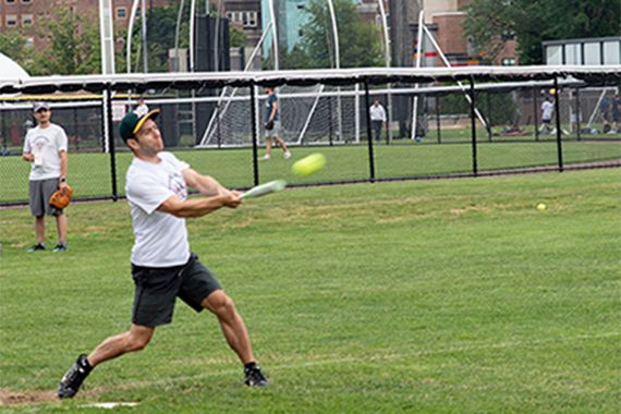 A man hits the ball in a softball game.